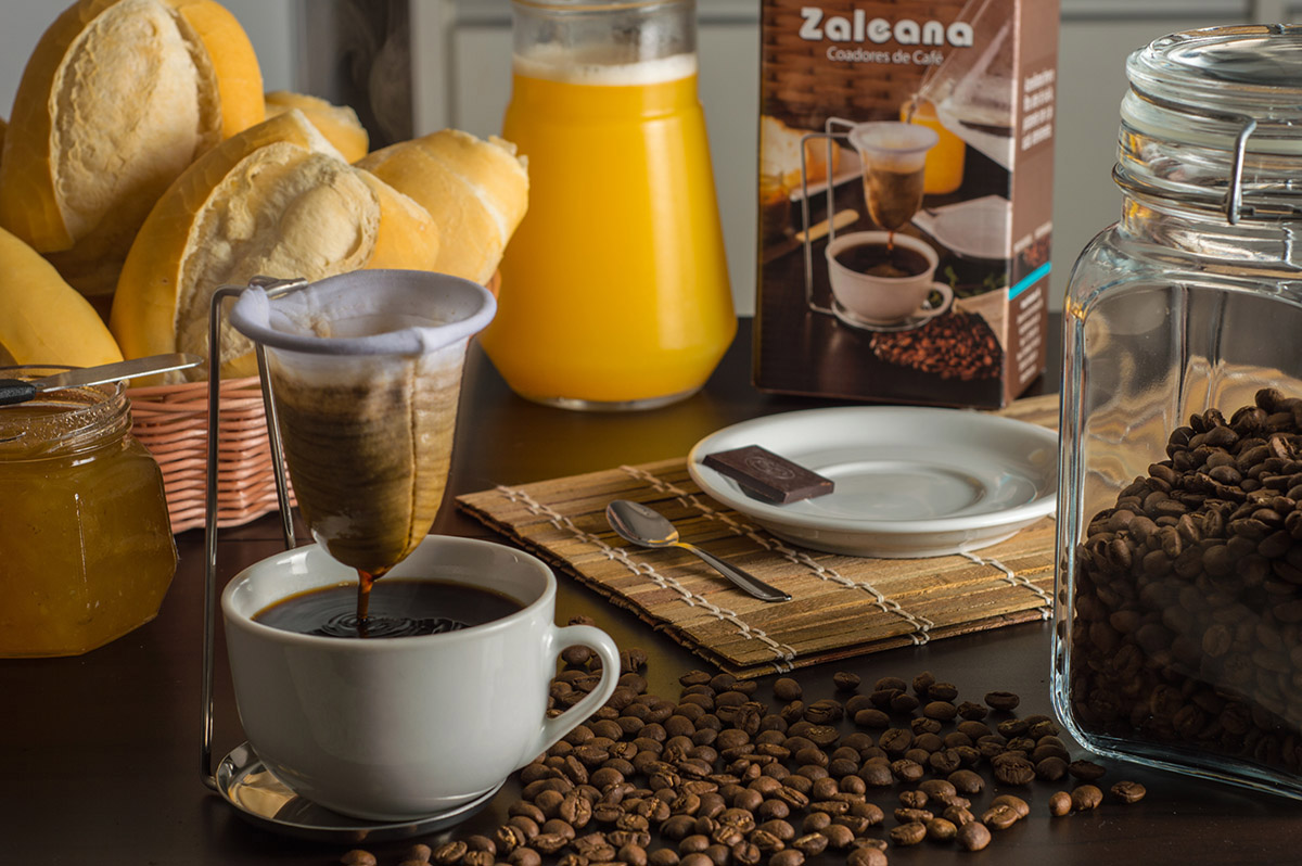 Café sendo coado em coador de pano com vapor subindo, em cozinha rústica